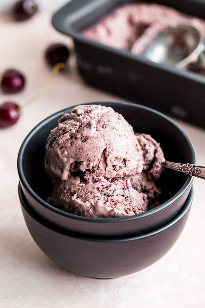 Up-close view of two scoops of cherry nice cream in a black bowl.