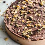 Angled view of a chocolate peanut butter nice cream cake with chocolate and crushed peanuts on top.