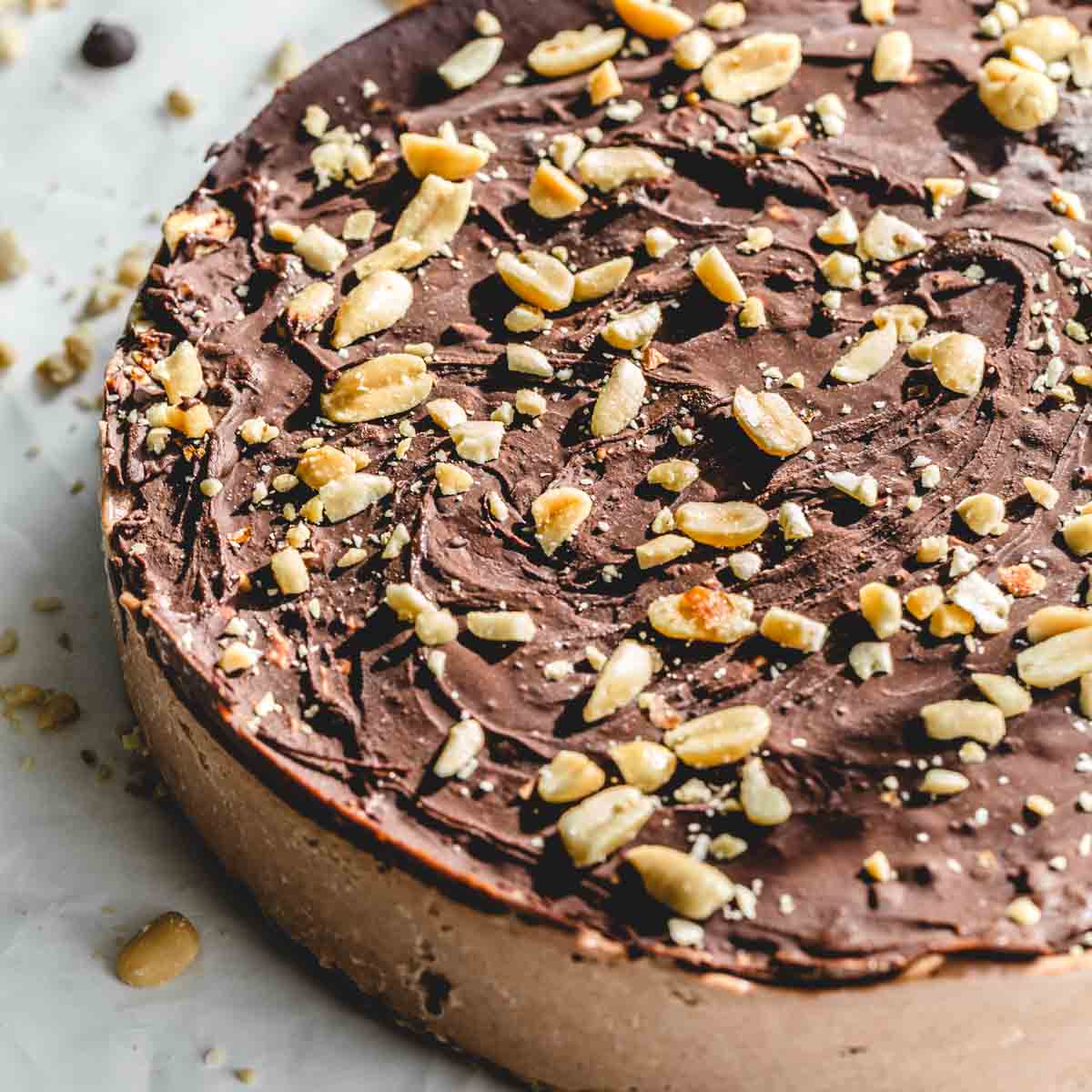 Angled view of a chocolate peanut butter nice cream cake with chocolate and crushed peanuts on top.