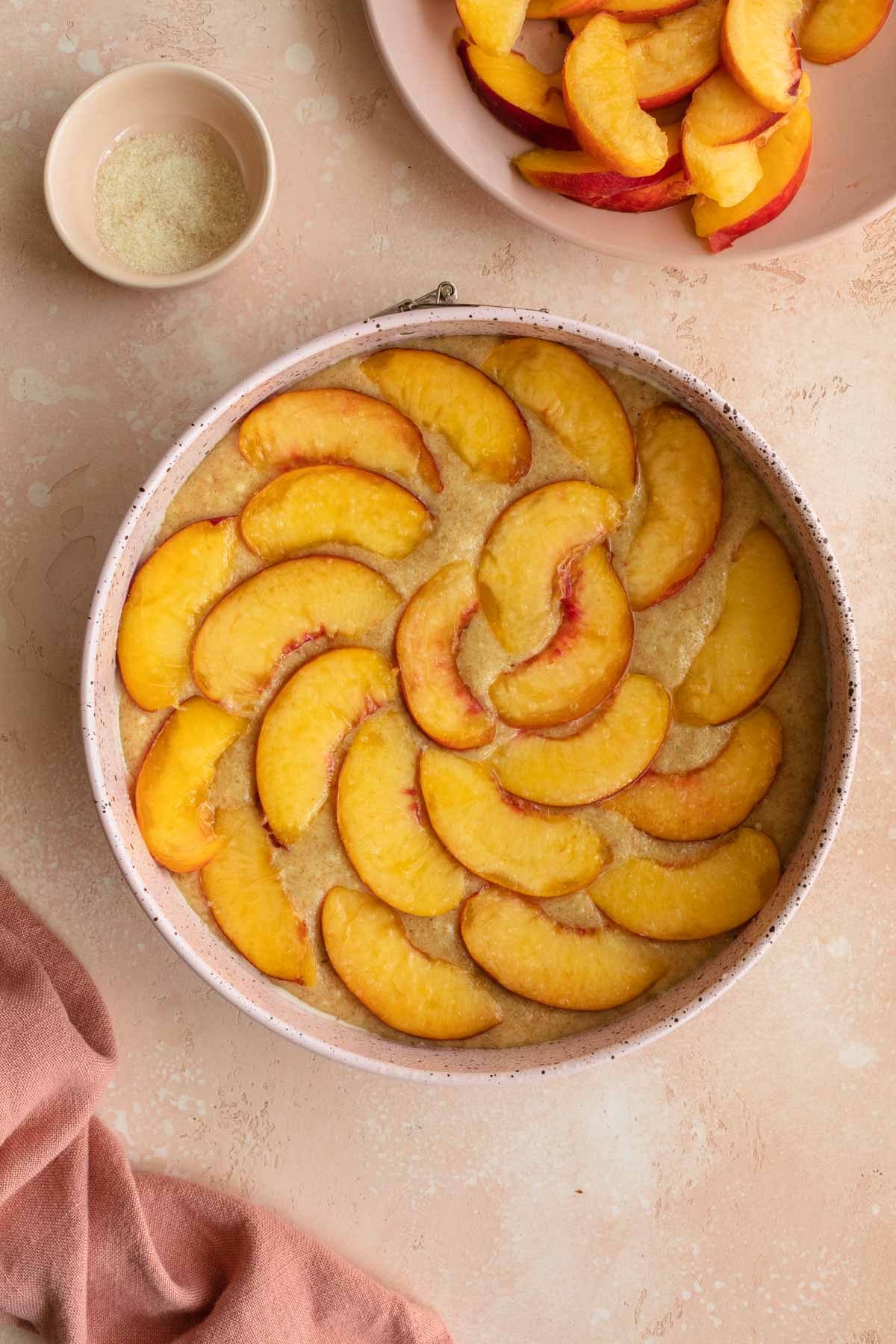 Cake batter in a springform pan topped with peach slices.