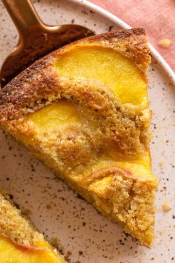 Slice of peach cake on a pink plate.