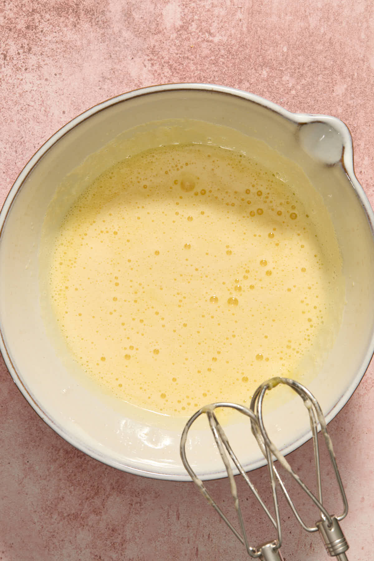 Eggs and sugar beaten together in a large white bowl.