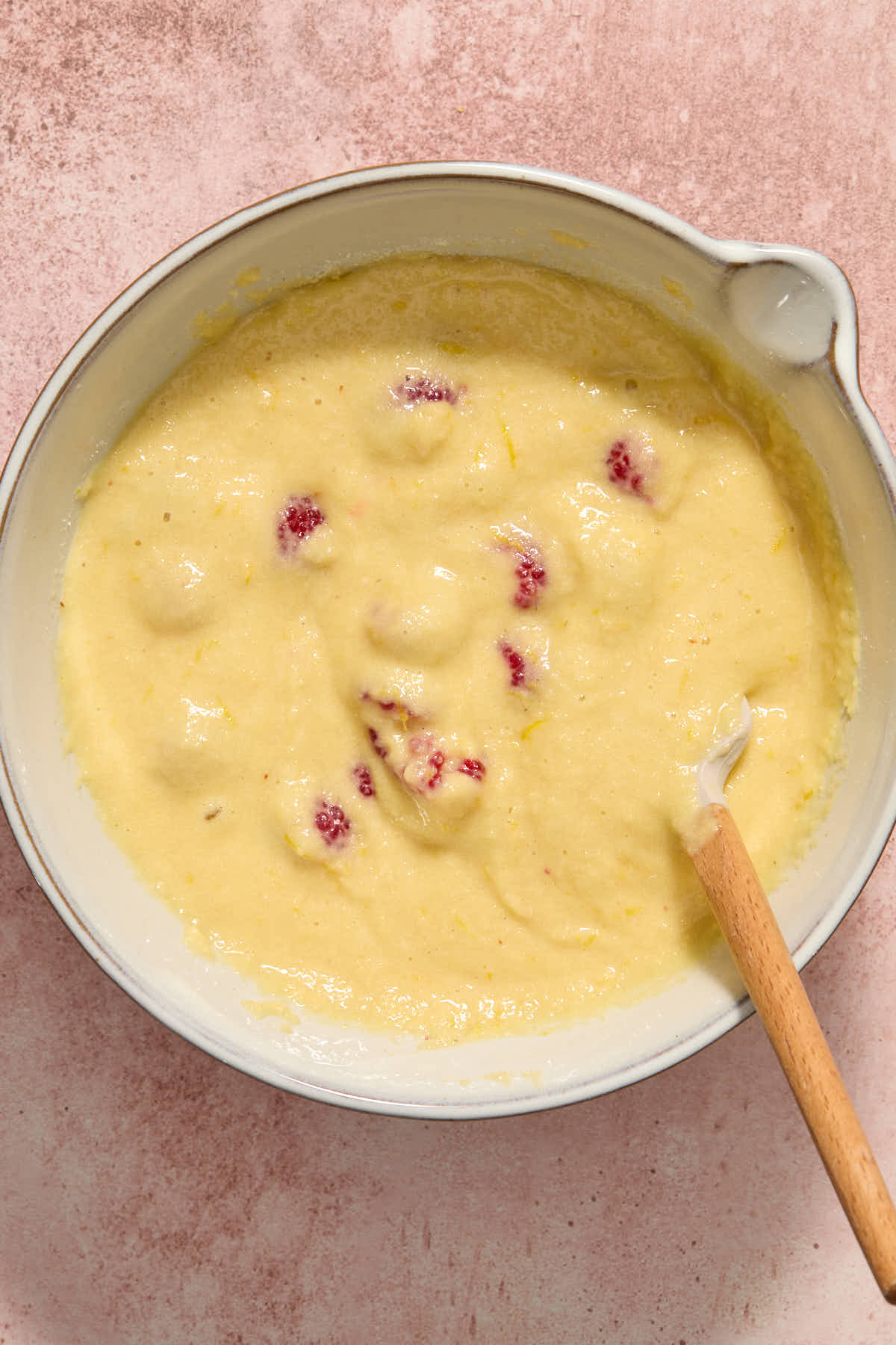 Raspberries folded into the cake batter with a spatula.