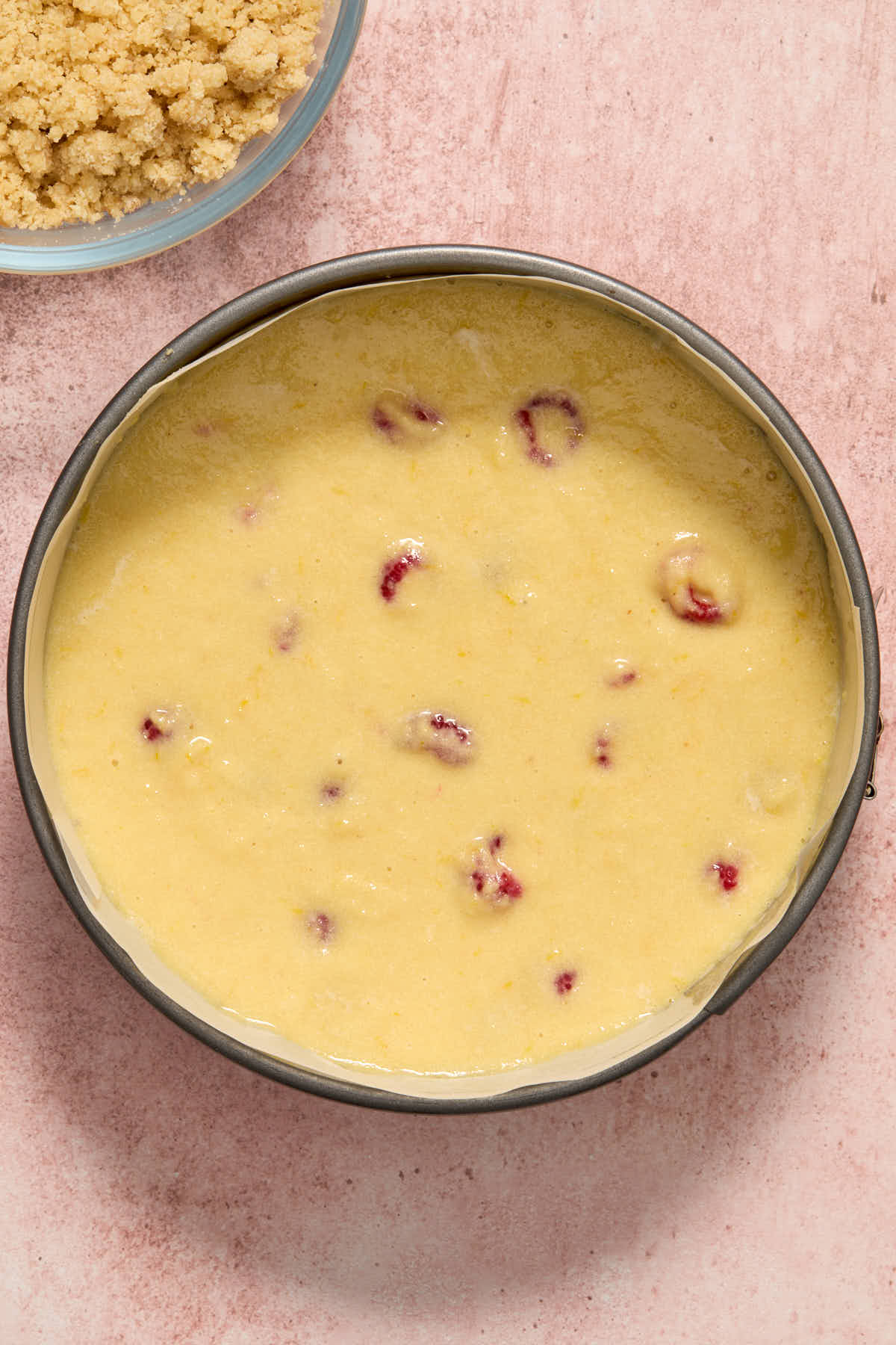 Cake batter spread out in a springform pan lined with parchment paper.