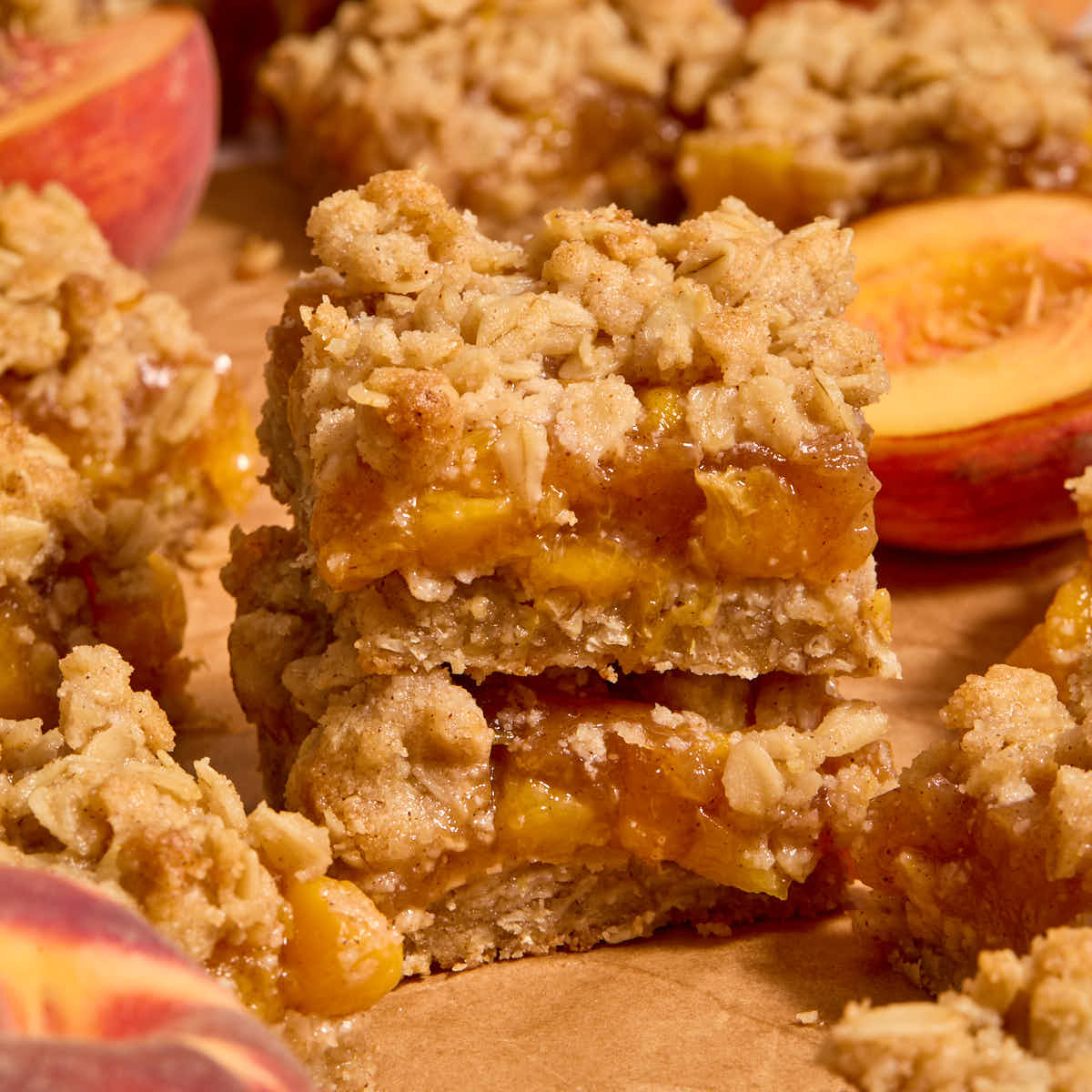 Two almond flour peach crisp bars stacked on top of each other on brown parchment paper.