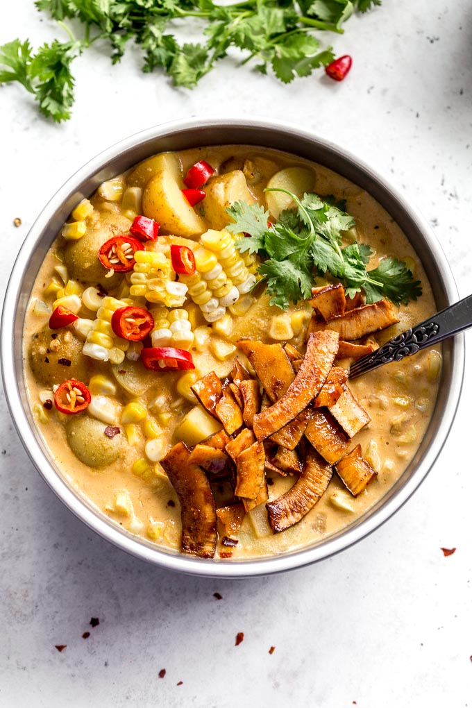 Up-close overhead view of corn chowder in a bowl with coconut bacon on top.