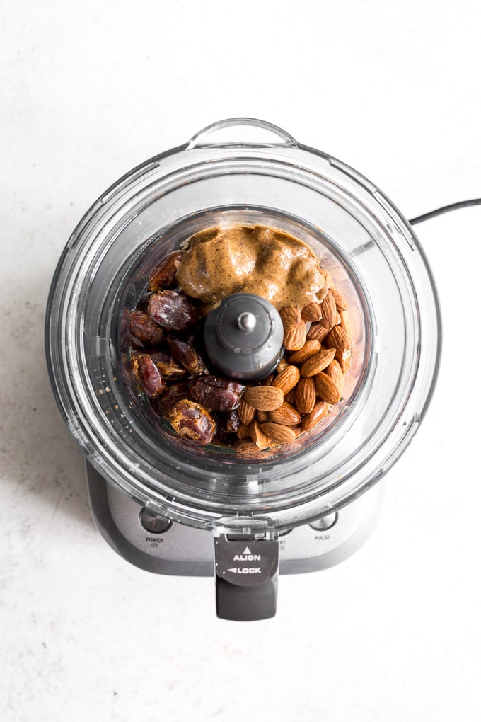 Ingredients for crust (dates, almonds, almond butter and maple syrup) in a food processor.