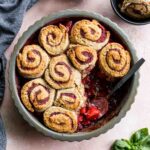 Overhead of strawberry basil cobbler in a pie dish with some removed with a spoon.