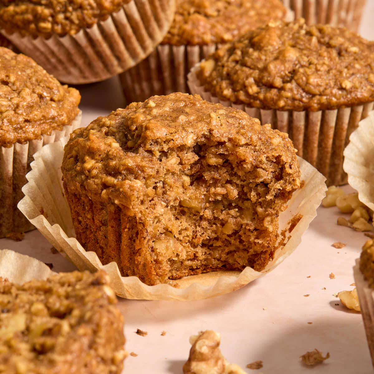 Side view of banana nut muffins with one on a parchment liner and a bite removed.