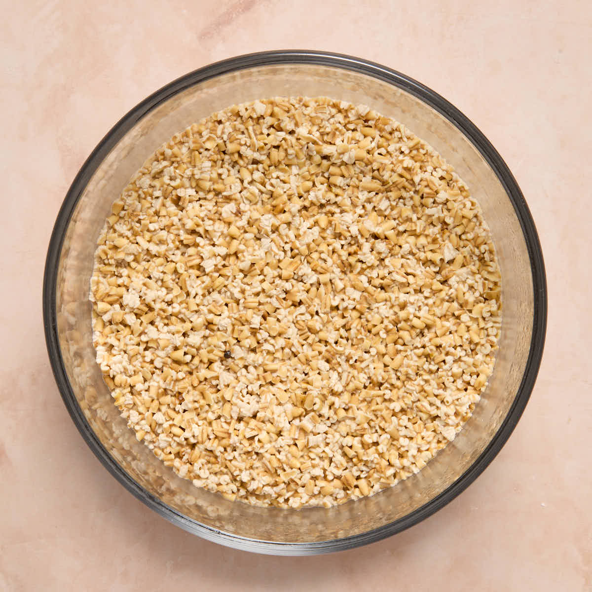 Oats fully soaked in almond milk in a glass bowl.