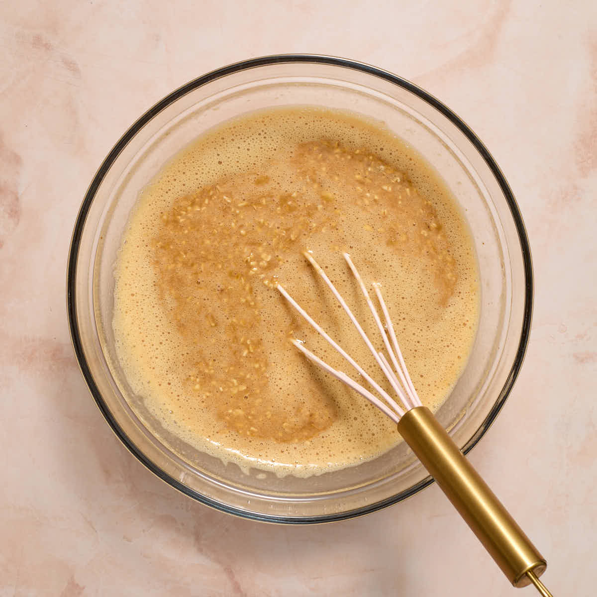 Wet ingredients mixed together in a large glass bowl with a whisk.