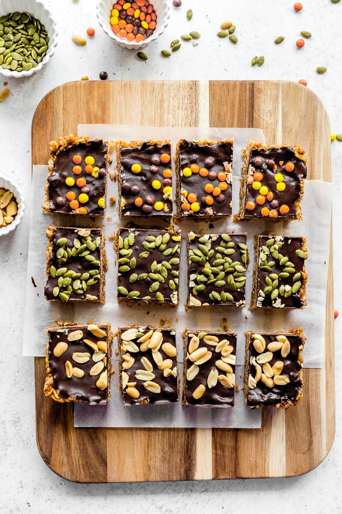 Overhead view of pumpkin krispie treats topped with chocolate and arranged on a wooden cutting board.