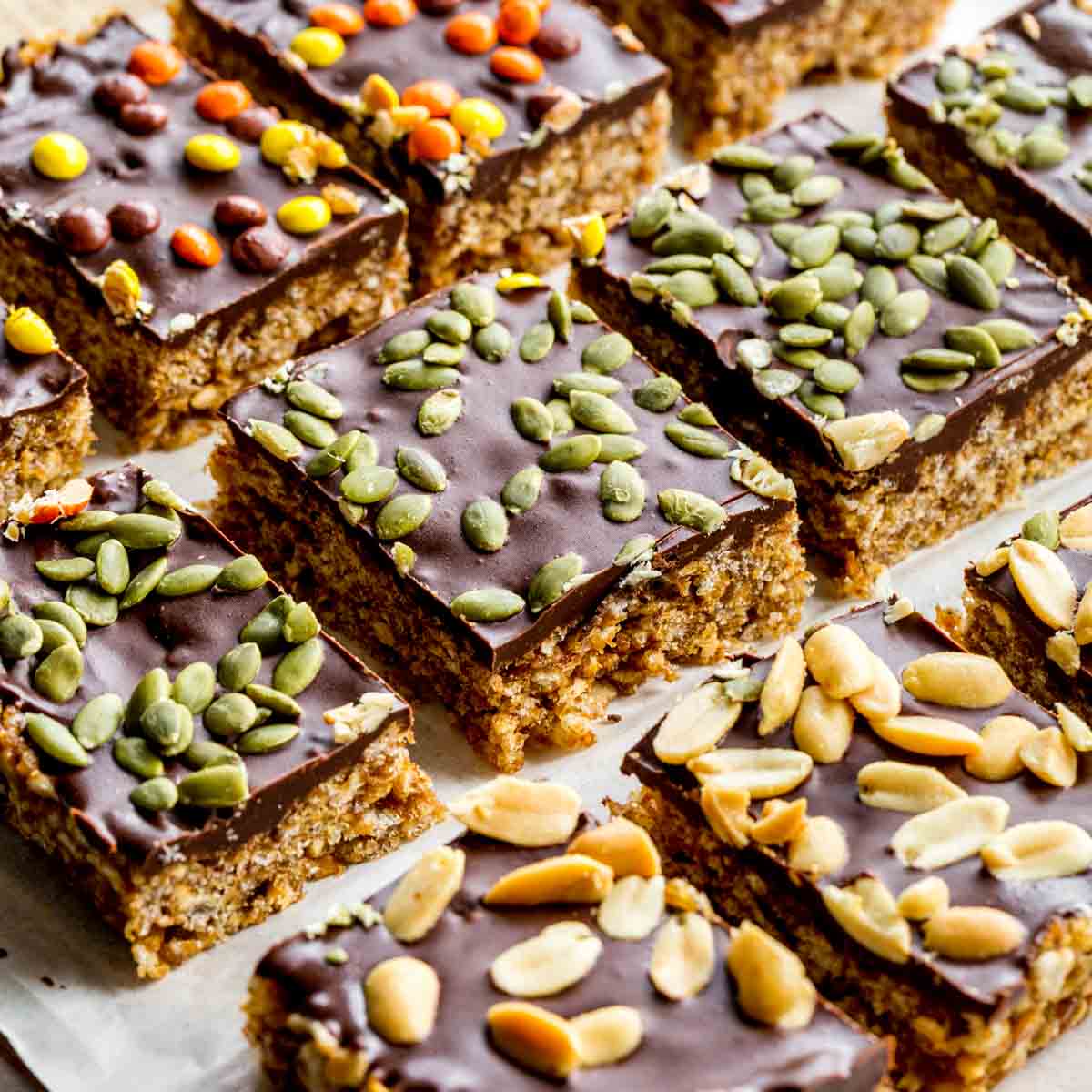 Angled view of pumpkin spice rice krispie treats arranged in rows on parchment paper.