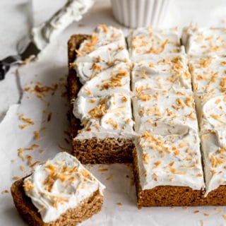 Vegan Chai Cake topped with coconut whip and toasted coconut and cut into squares.