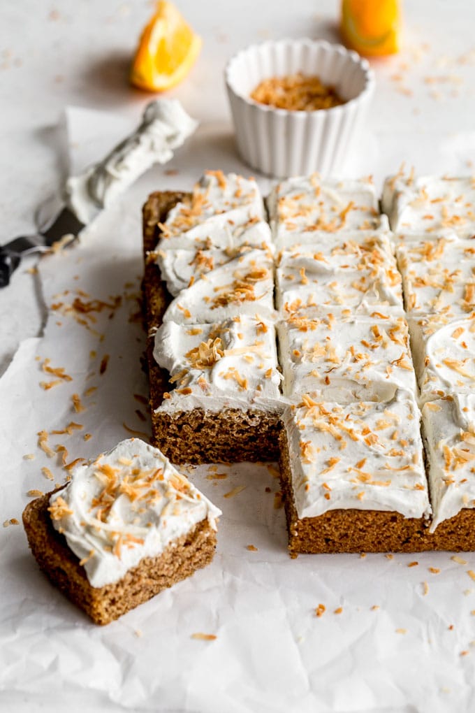 Vegan Chai Cake topped with coconut whip and toasted coconut and cut into squares.