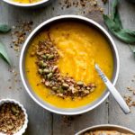 Overhead view of Golden Beet Soup topped with granola and arranged on a grey board.