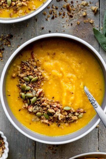 Overhead of golden beet soup in a bowl with savory granola on top.