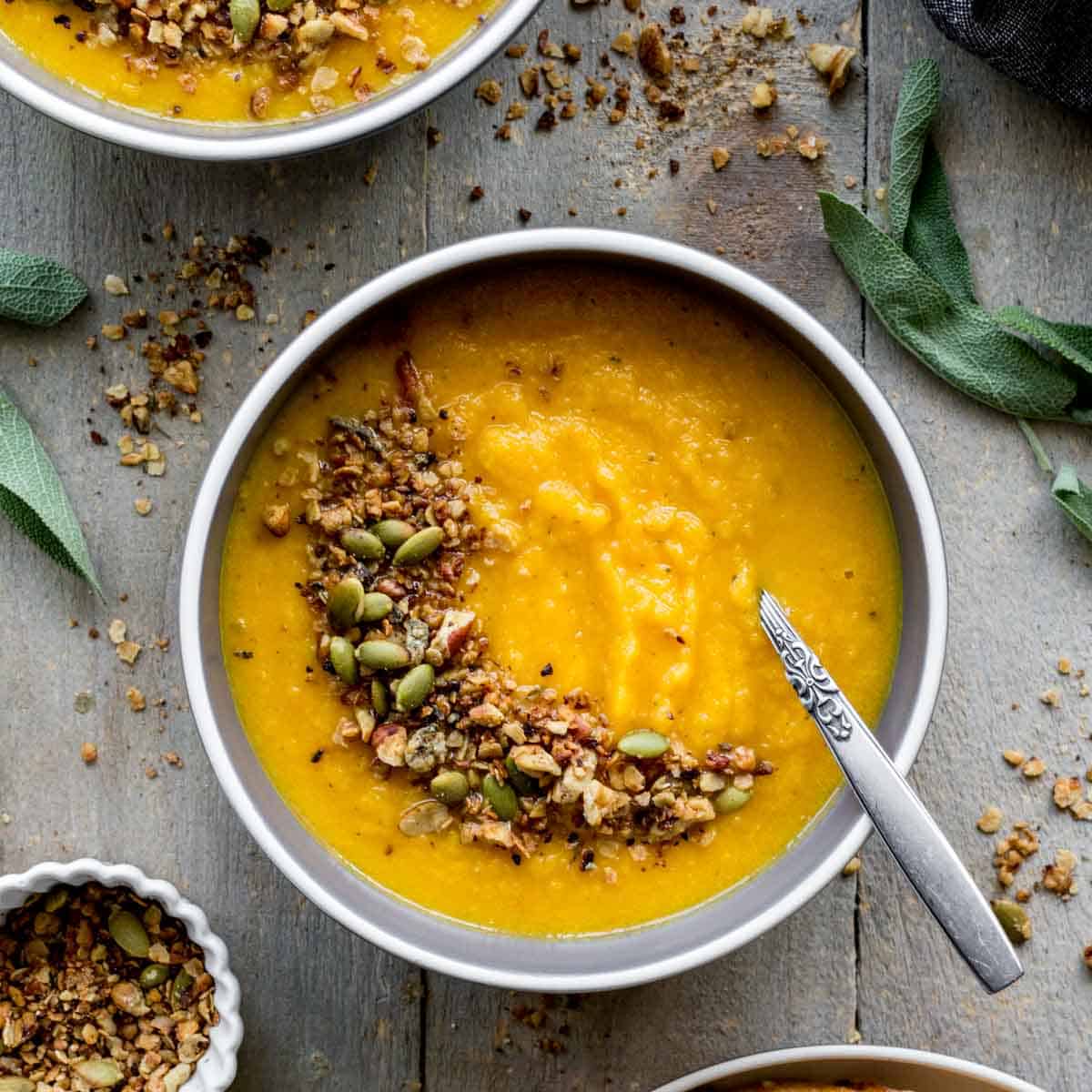 Overhead of golden beet soup in a bowl with savory granola on top.