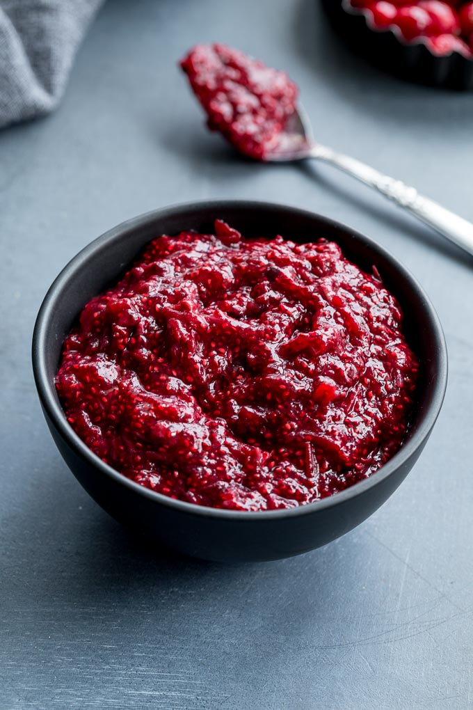 Up-close view of healthy cranberry sauce in a small black bowl.