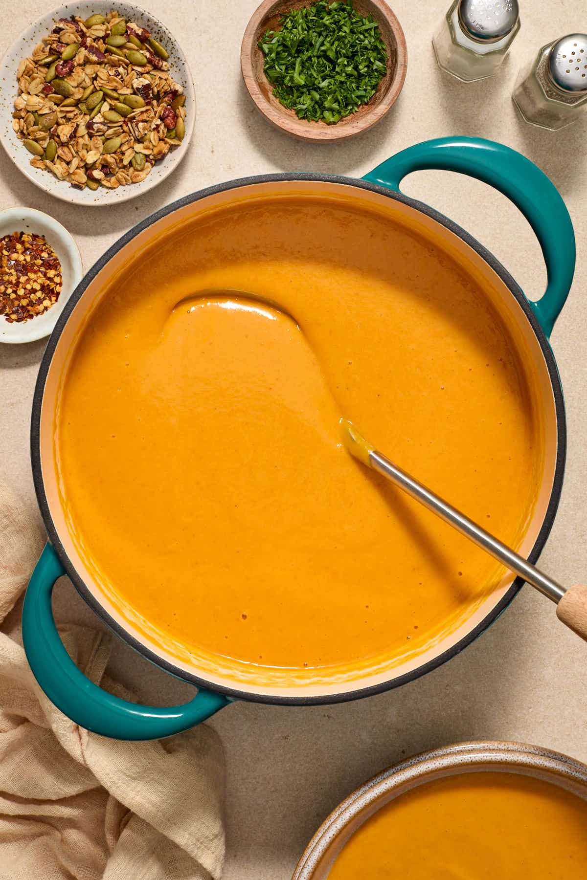 Soup warmed in a large pot with a ladle and soup toppings surrounding the pot.