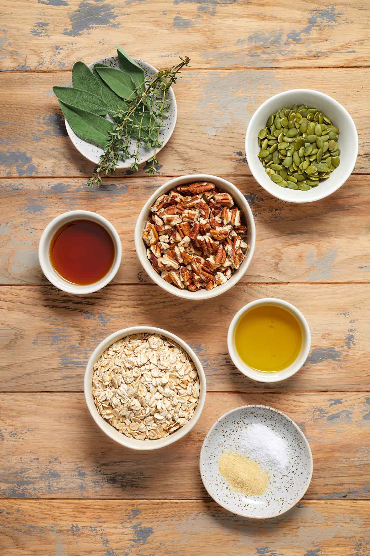 Ingredients to make savory granola arranged individually on a wooden table.