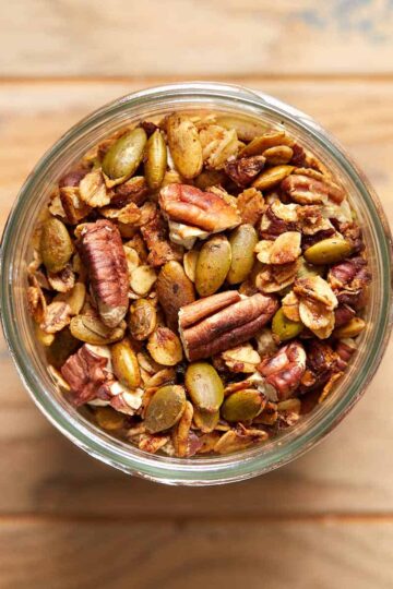 Savory granola in a glass jar on a wooden table.