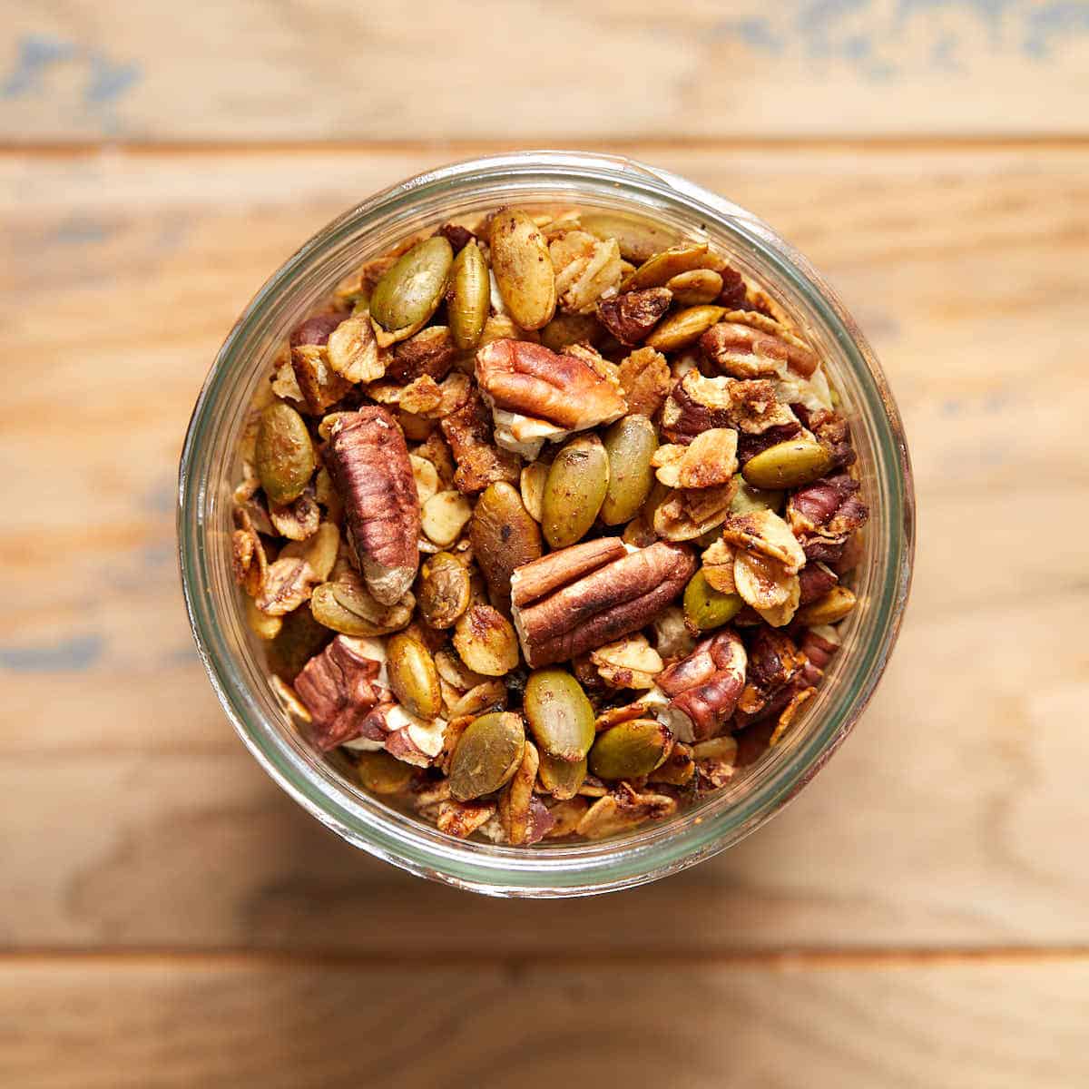 Savory granola in a glass jar on a wooden table.