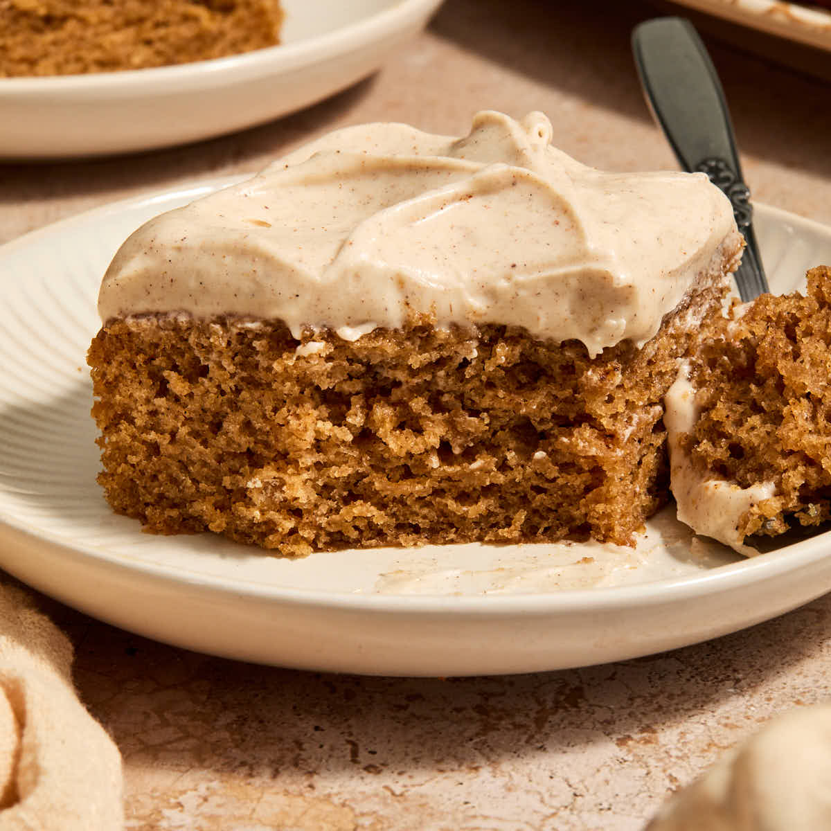 A piece of vegan chai spice cake on a plate with a forkful removed.