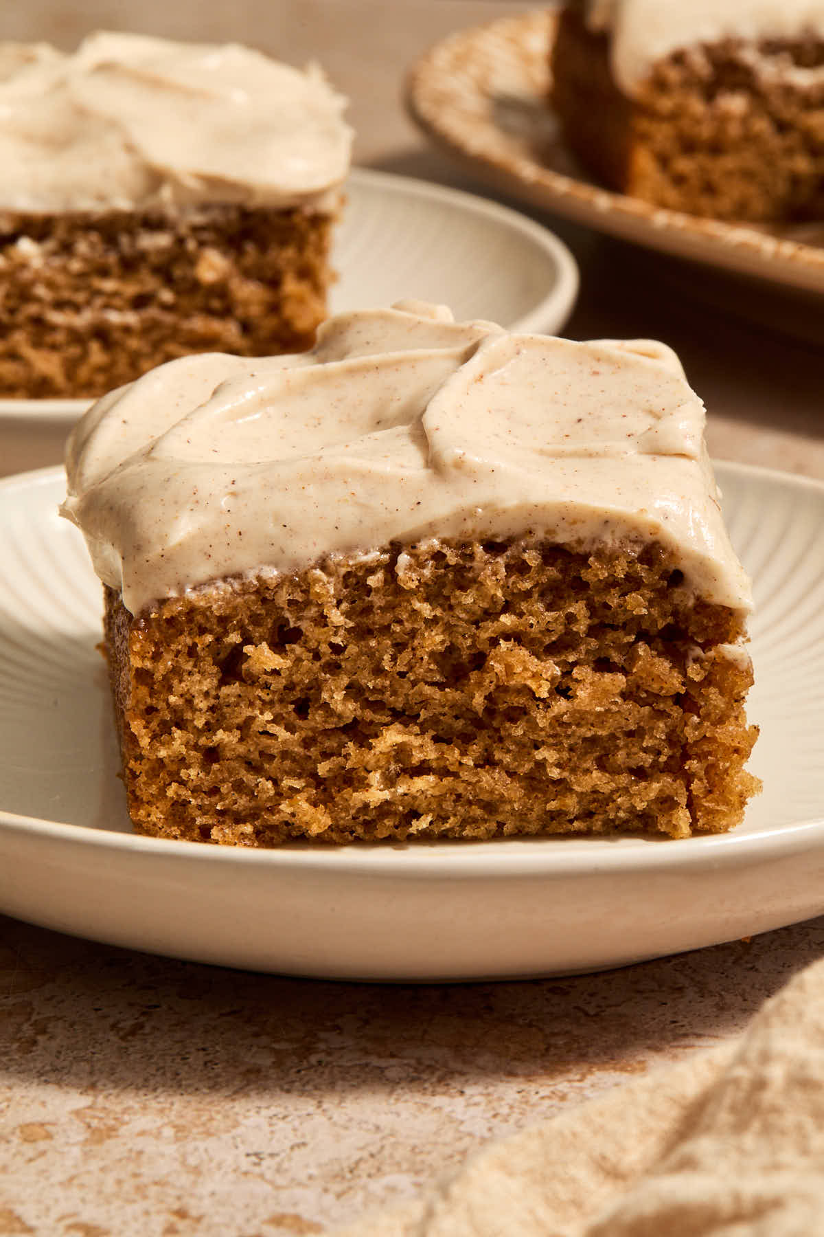 Side view of a piece of chai cake on a plate with pieces in the background.