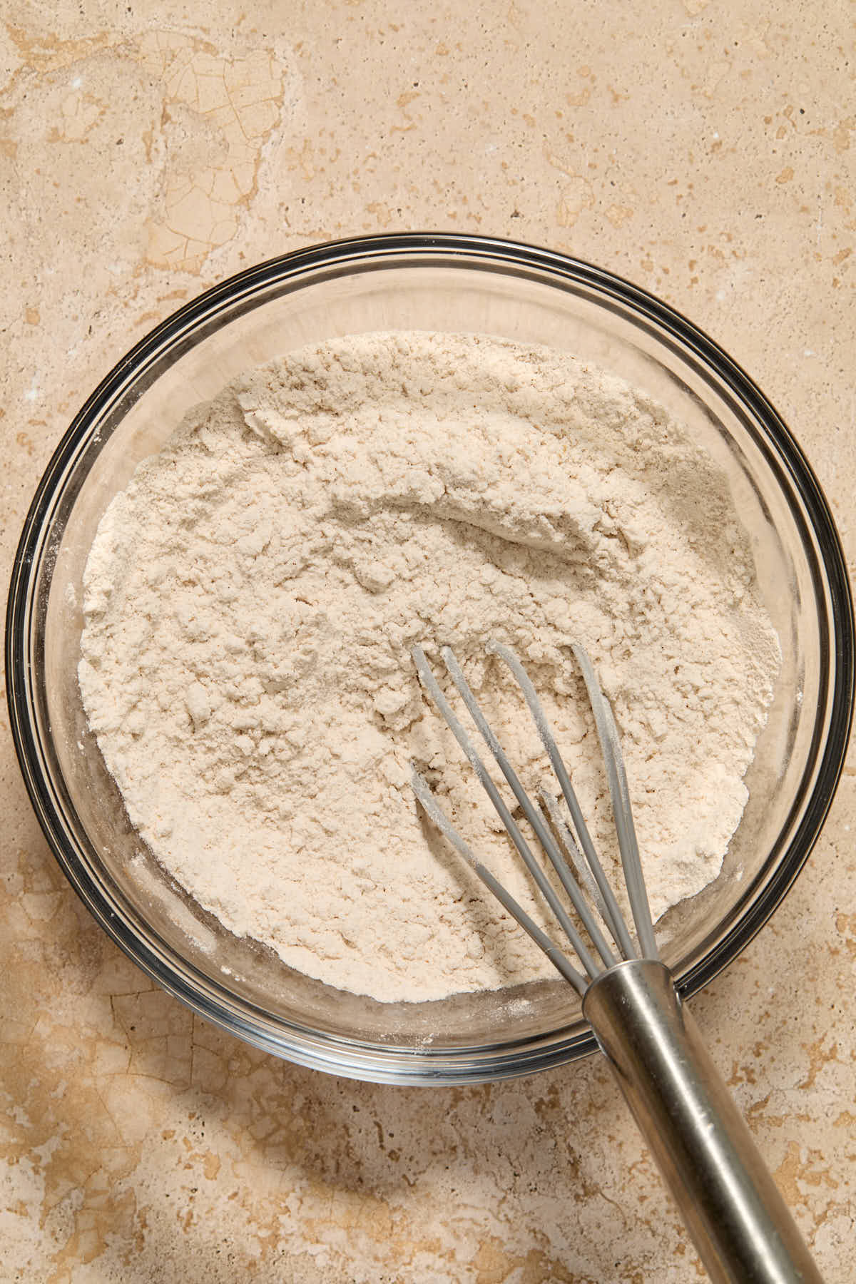Dry cake ingredients whisked together in a glass bowl.
