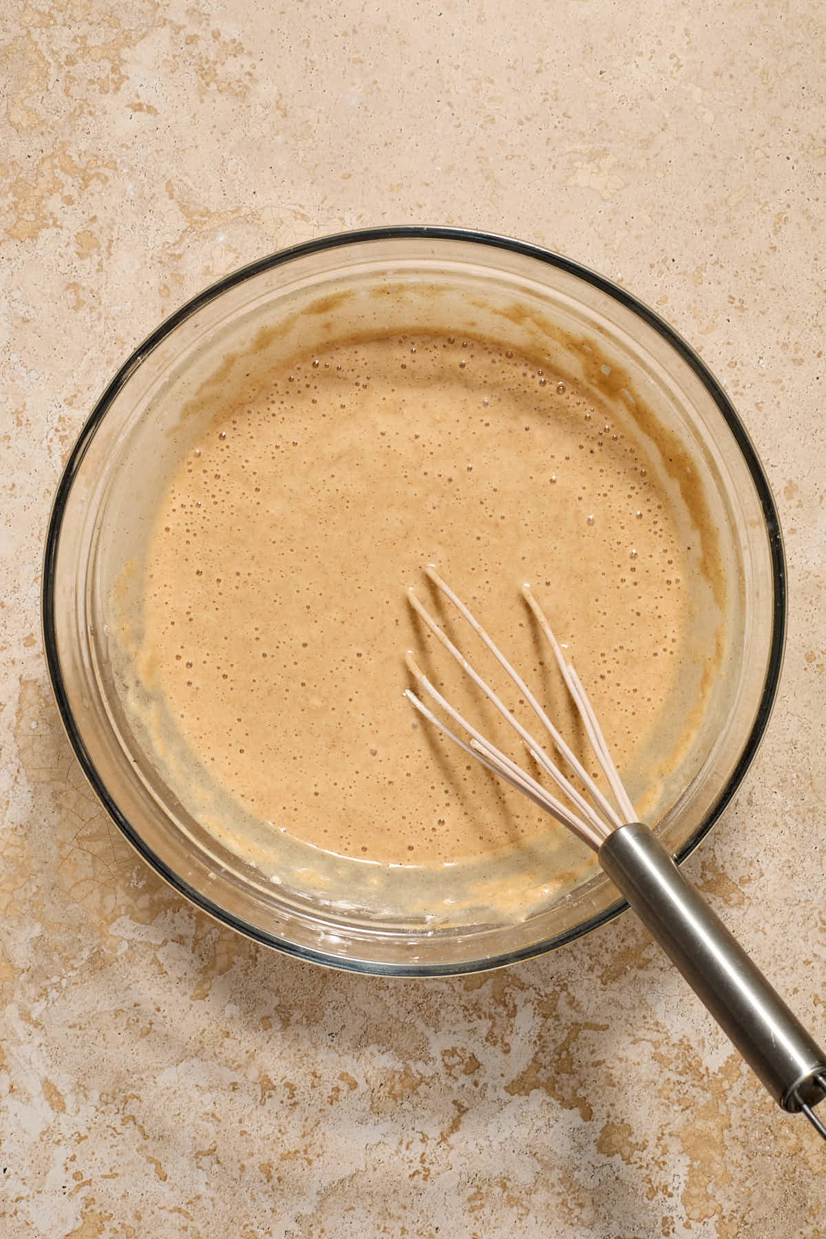 Batter mixed together in a glass bowl with a whisk.