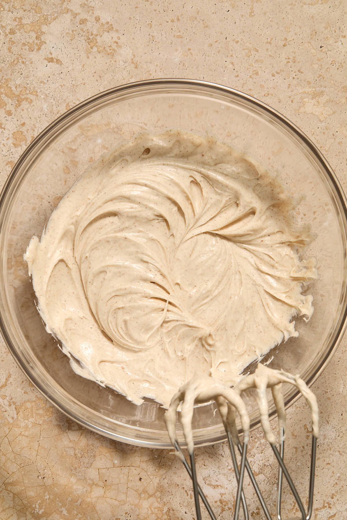 Frosting whipped together in a glass bowl with beaters in the frame.