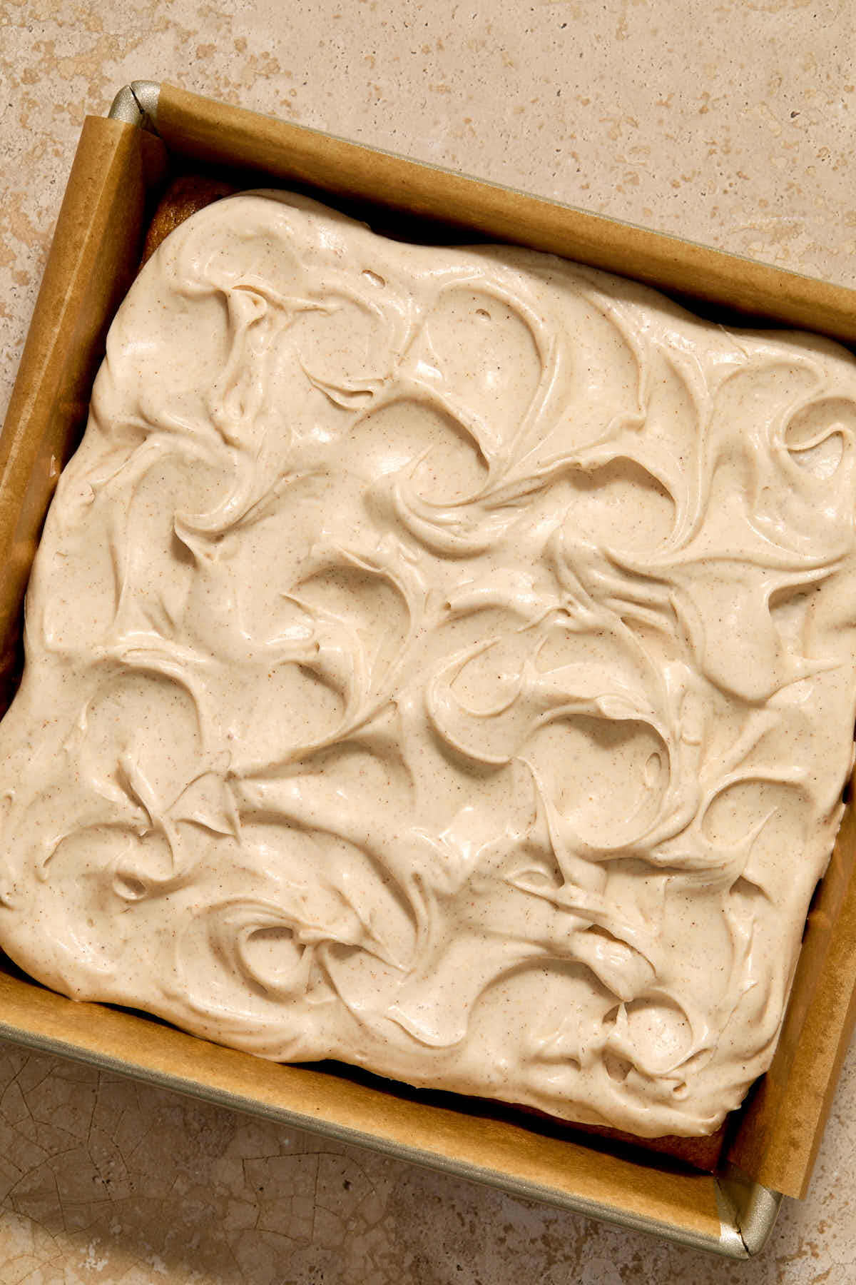 Frosting spread out on top of the cake in the pan.