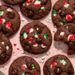 Overhead view of chocolate peppermint cookies with extra candy cane pieces and chocolate chips on top.