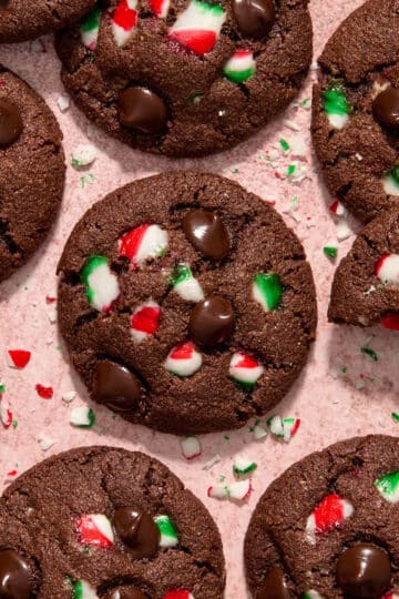 Overhead view of chocolate peppermint cookies with extra candy cane pieces and chocolate chips on top.