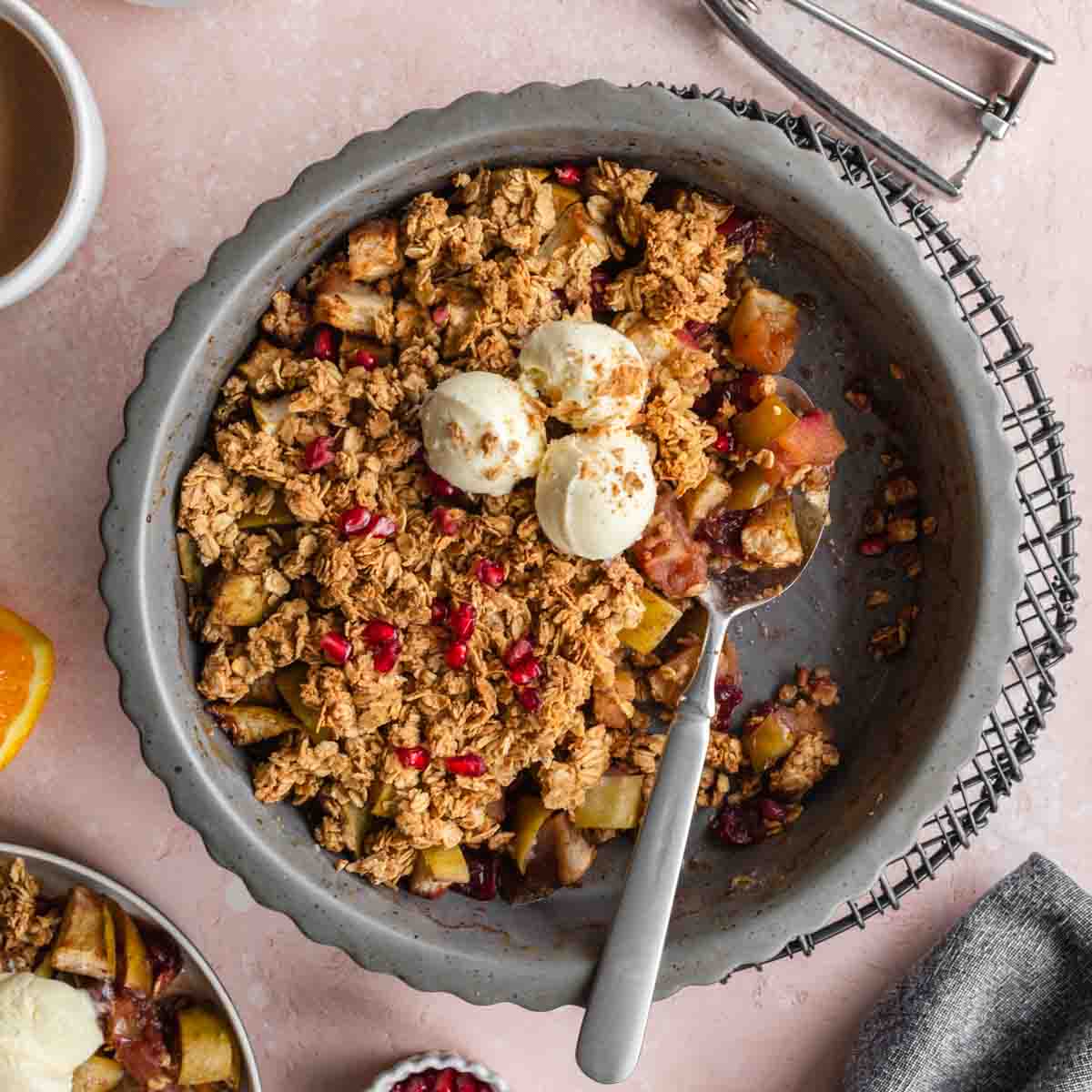 Overhead of cranberry apple crisp in a pie dish with some removed and ice cream on top.