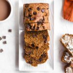 Overhead of whole wheat pumpkin bread sliced on a white platter.