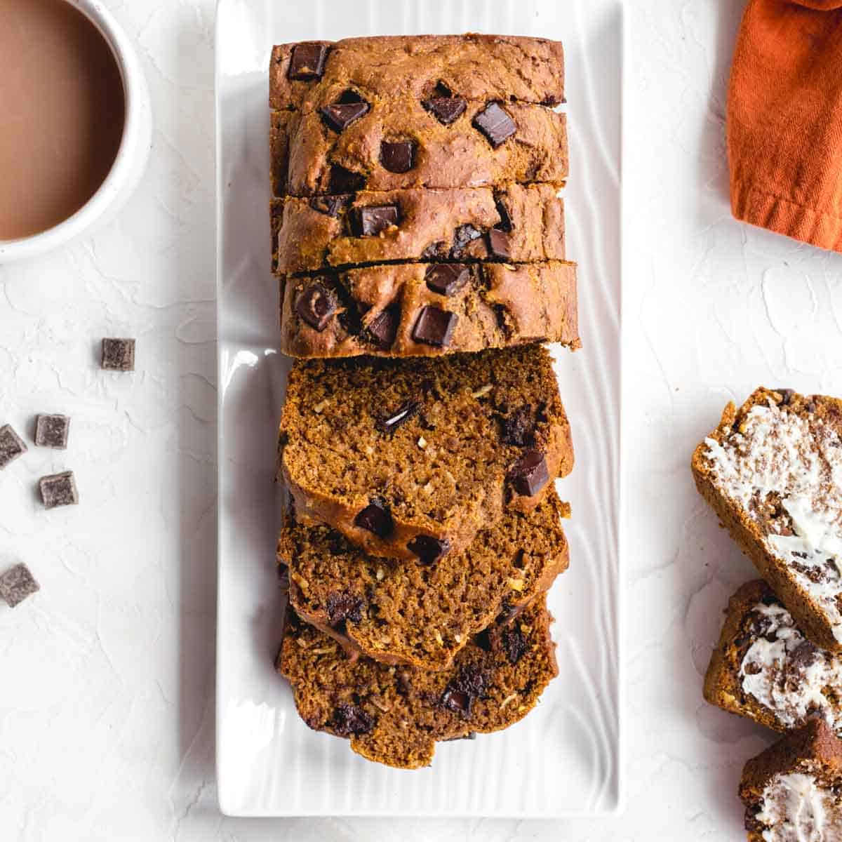Overhead of whole wheat pumpkin bread sliced on a white platter.