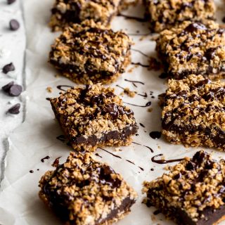 Chocolate Oat Bars topped with chocolate and arranged on parchment paper.