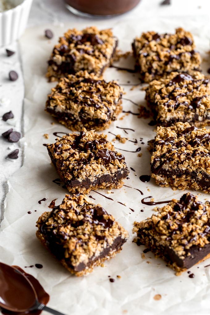 Chocolate oat bars arranged on a sheet of parchment paper and drizzled with melted chocolate.
