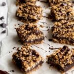 Angled view of chocolate oat bars on parchment paper with melted chocolate drizzled over top.