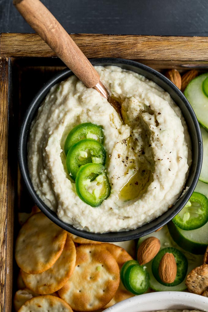 Up-close view of jalapeño lime white bean dip in a black bowl.