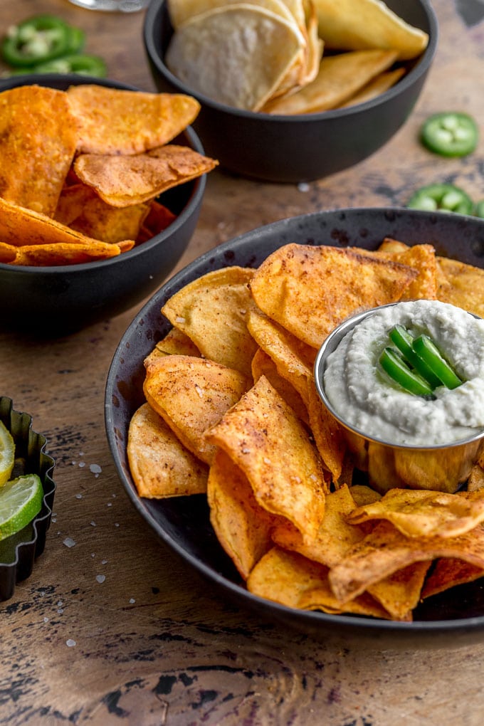 Side view of savoury air fryer tortilla chips arranged in black bowls.