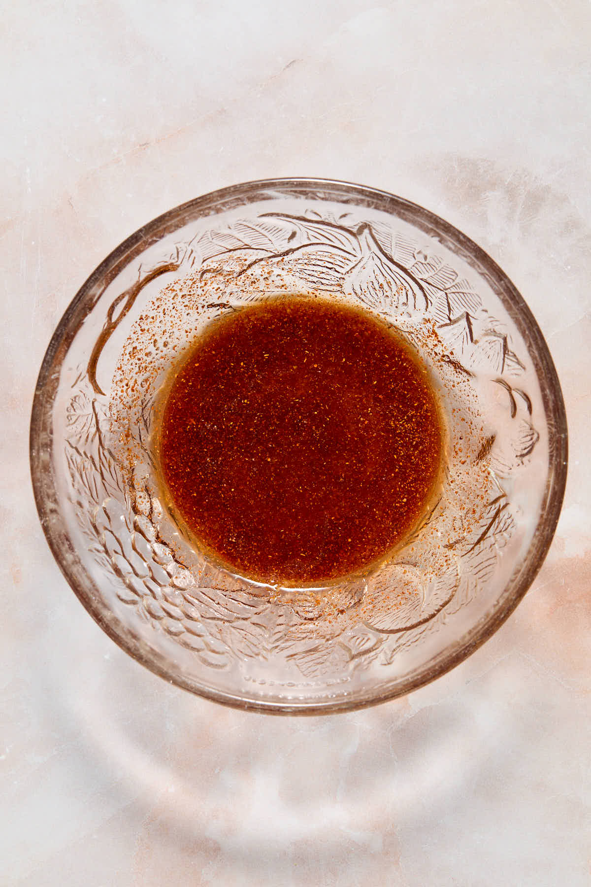 Oil and seasonings mixed together in a small glass bowl.
