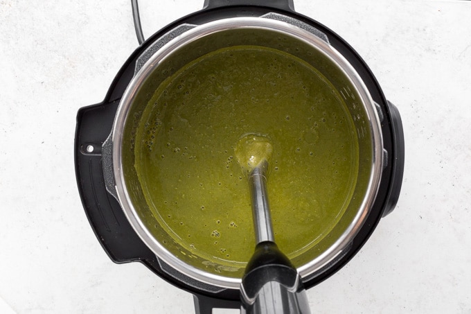 Green pea soup being pureed with immersion blender in the Instant Pot.
