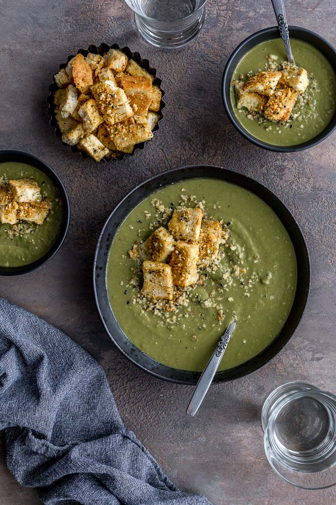 Creamy vegan pea soup served up in black bowls and topped with croutons.