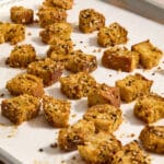 Homemade sourdough croutons on a parchment lined baking sheet.