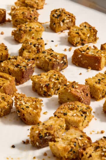 Homemade sourdough croutons on a parchment lined baking sheet.