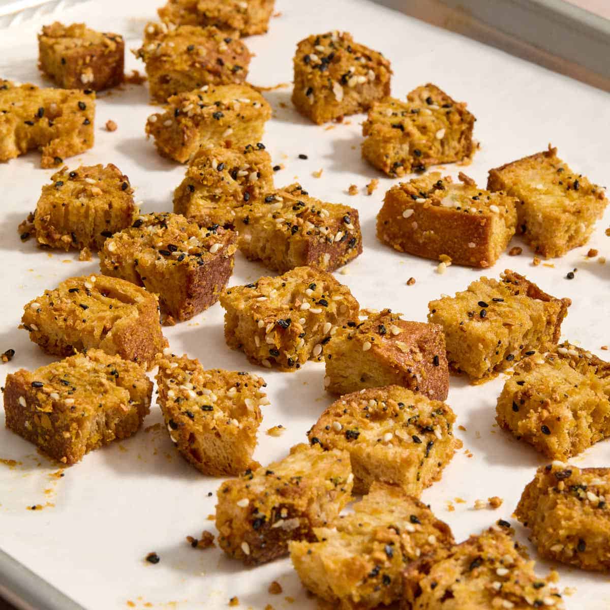 Homemade sourdough croutons on a parchment lined baking sheet.
