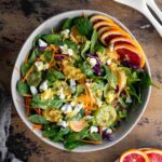 Overhead of winter citrus salad in a large bowl and topped with dressing.